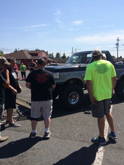 1989 Ford Bronco - A lifted Ford Bronco is parked at an outdoor event with several people standing around it.