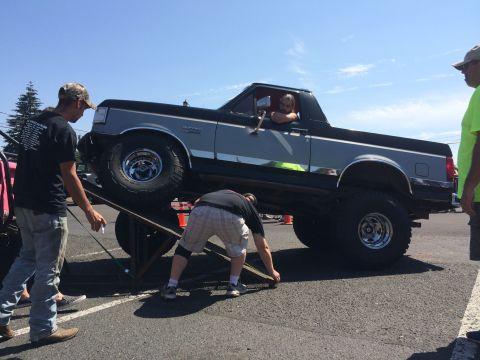 1989 Ford Bronco - A lifted 1989 Ford Bronco is positioned on a ramp at an outdoor event.