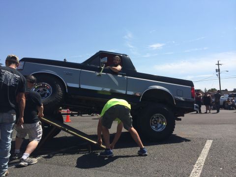 1989 Ford Bronco - A 1989 Ford Bronco is being lifted by a jack at an outdoor event.