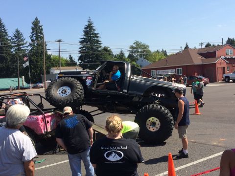 1989 Ford Bronco - A heavily modified truck with oversized tires is displayed at an outdoor event, with spectators gathered around.