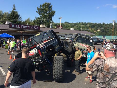 1989 Ford Bronco - Modified off-road trucks are displayed at an outdoor event with spectators.
