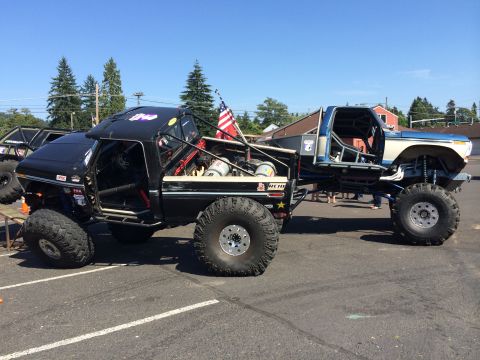1989 Ford Bronco - Custom off-road trucks with extensive modifications and large tires are displayed outdoors.