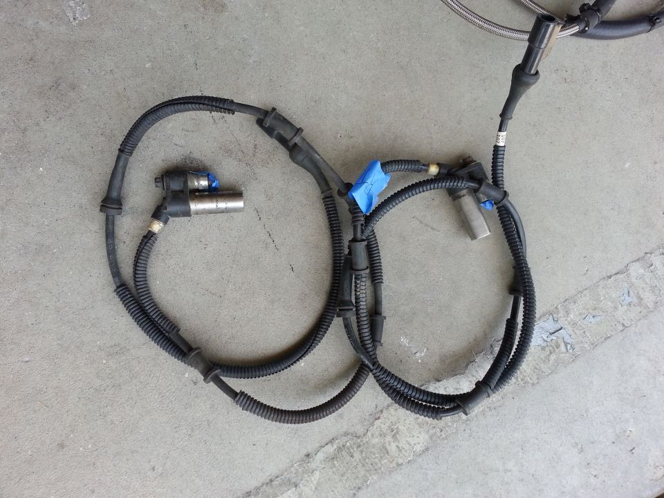Automotive wiring harness with two sensors, one blue-taped, on concrete