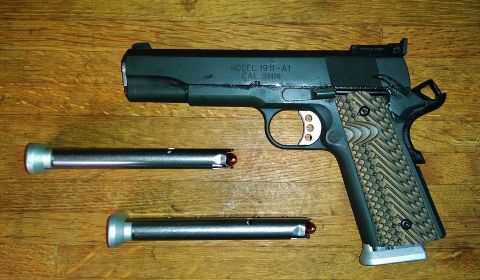 1996 Ford Bronco - A pistol and two magazines are displayed on a wooden surface. The pistol is marked 'MODEL 1911-A1 CAL 9MM'.