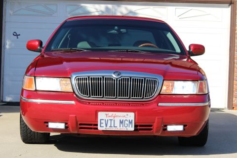 2002 Mercury Grand Marquis - Front view of a red 2002 Mercury Grand Marquis, a chrome grille and a custom 'EVIL MGM' license plate.