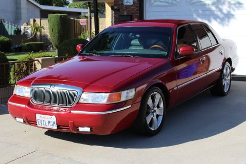 2002 Mercury Grand Marquis - A red 2002 Mercury Grand Marquis is parked in front of a garage and house.