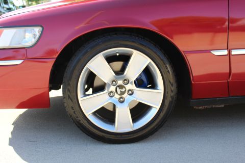 2002 Mercury Grand Marquis - Close-up of a red car's front wheel and fender assembly.