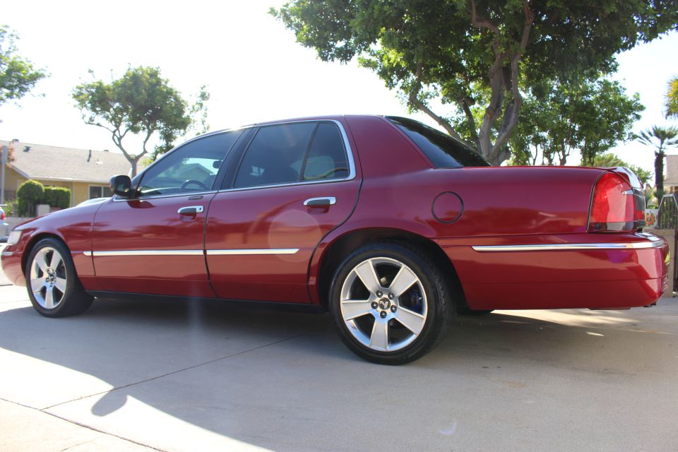 Red 2002 Mercury Grand Marquis sedan, rear quarter view, chrome trim, aftermarket wheels, clean condition