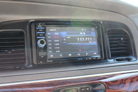 2002 Mercury Grand Marquis - Close-up of a car's dashboard, focusing on the aftermarket touchscreen radio and wood grain accents.