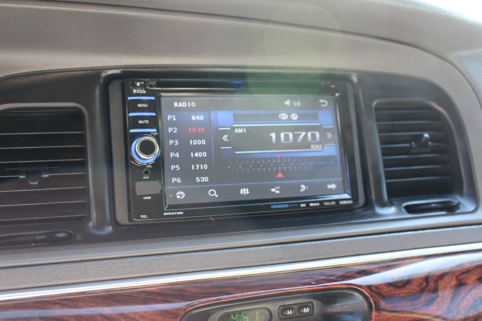 Dashboard with touchscreen radio and wood trim. Radio shows AM 1070