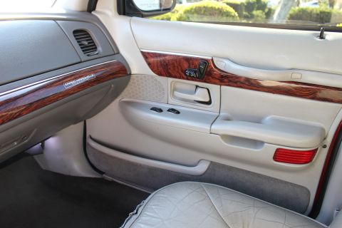 2002 Mercury Grand Marquis - Close-up of the interior door panel, wood trim and the 'Grand Marquis' badge, indicative of a 2002 model.