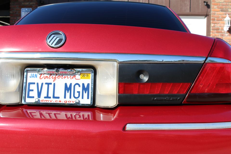 Rear of a red 2002 Mercury Grand Marquis with a California license plate that says EVIL MGM