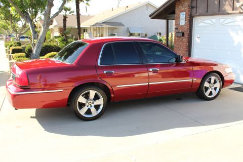 2002 Mercury Grand Marquis - Side view of a red 2002 Mercury Grand Marquis parked in a residential driveway.
