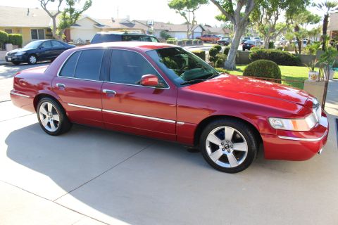 2002 Mercury Grand Marquis - A red 2002 Mercury Grand Marquis is parked in a suburban driveway on a sunny day.