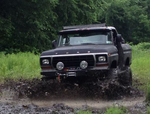 1979 Ford Bronco - This modified Ford truck is navigating a muddy trail with its front tires deep in the muck.