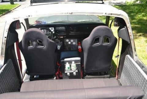 1979 Ford Bronco - The interior of the vehicle features racing seats and a center console with drinks and a fire extinguisher.