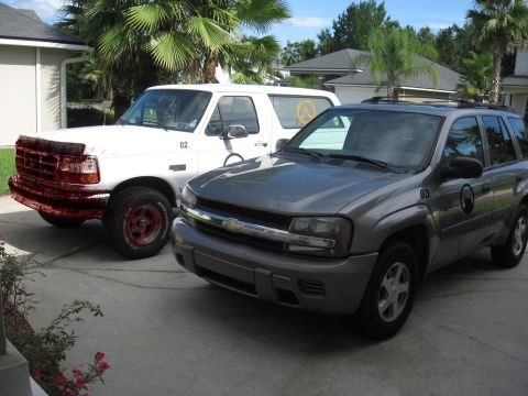 1994 Ford Bronco - Two SUVs, a white Ford Bronco and a gray Chevrolet Trailblazer, are parked in a driveway.