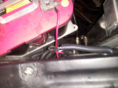 1976 Ford Ranchero - Close-up view of a car battery and its electrical connections, including wiring and a wire loom.