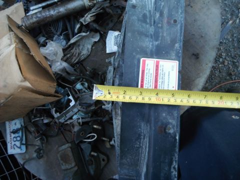 1980 Ford Bronco - Scrap metal and car parts are piled up, with a measuring tape and a warning label visible.
