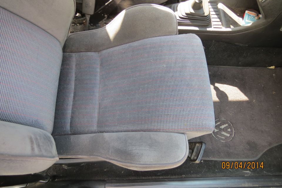 Volkswagen interior showing patterned fabric seats and a floor mat with a VW logo