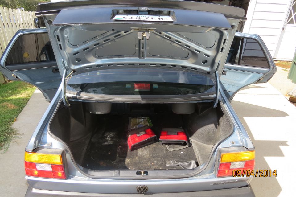 1990 Volkswagen Jetta trunk open, showing two red bags and spare tire well