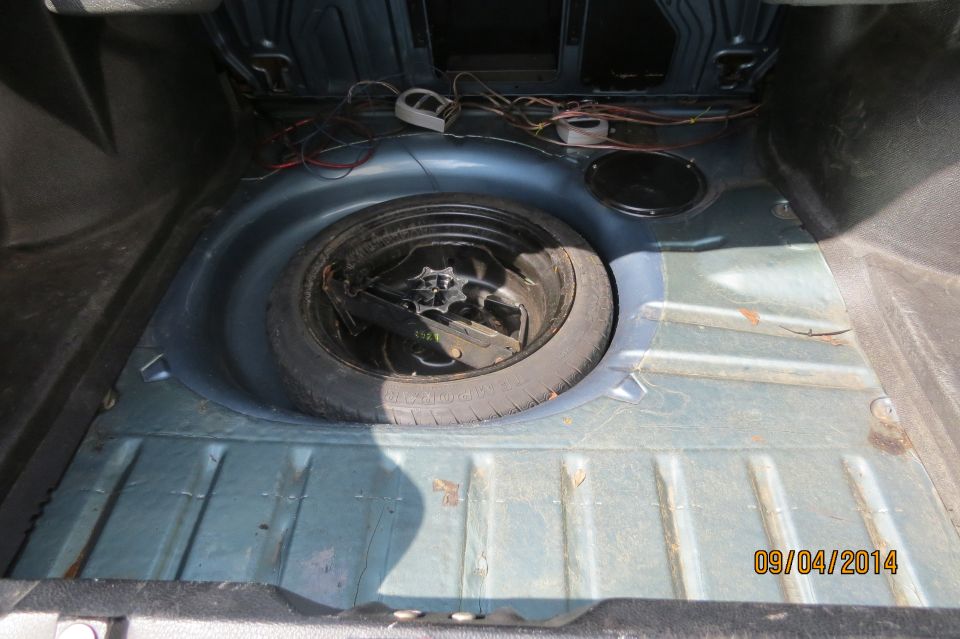 car trunk showing spare tire well and wiring