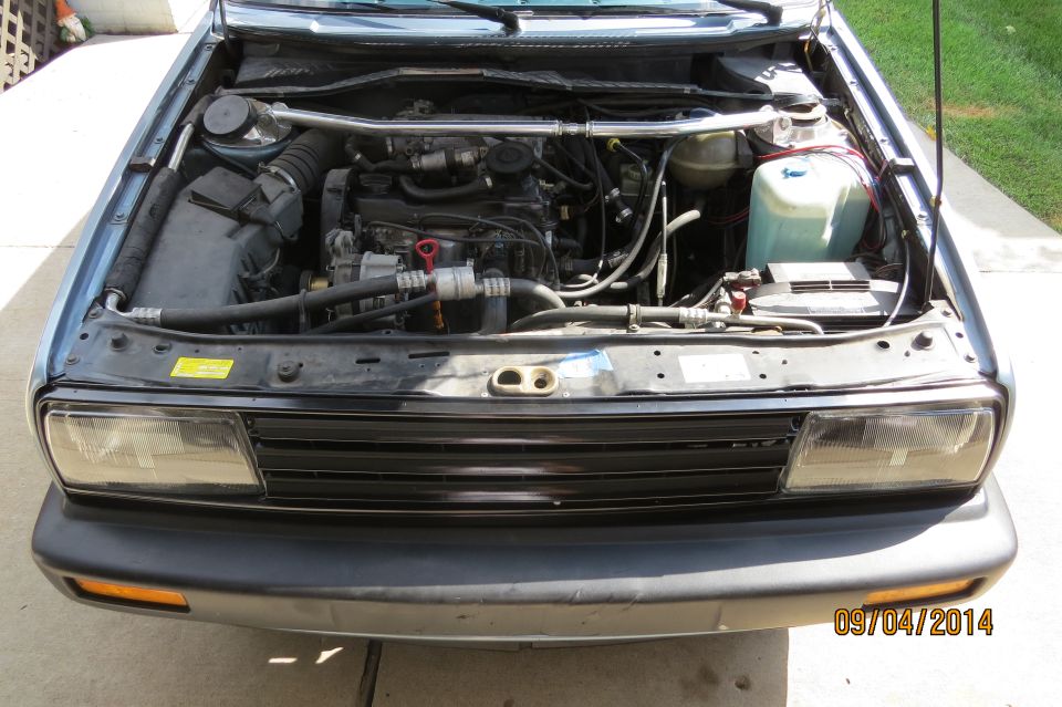 Blue 1990 Volkswagen Jetta engine bay with visible engine components and battery