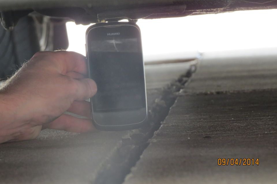 hand holding phone under car