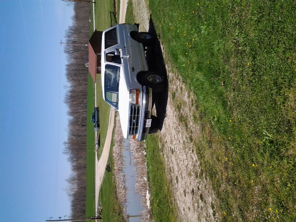 White Ford Bronco parked on gravel drive in rural yard, front 3/4 view, image rotated sideways