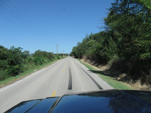 1982 Ford Bronco - Rural road with tire tracks visible under a clear blue sky.
