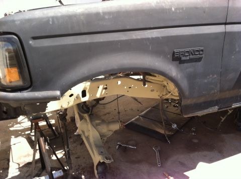 1995 Ford Bronco - The front fender and suspension of a 1995 Ford Bronco are visible, with tools nearby suggesting ongoing work.