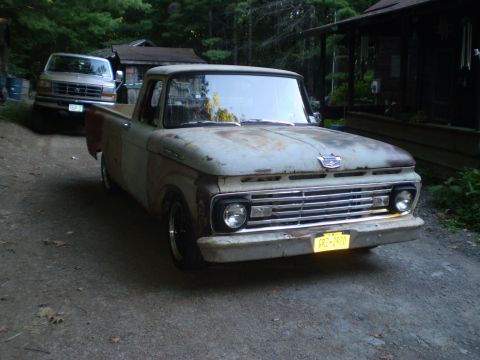 1979 Ford Bronco - A rusty 1962 Ford F-100 pickup truck sits in a driveway with another vehicle parked behind it.
