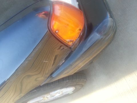 1991 Ford Festiva - Close-up of a damaged tail light and rear fender on a dark blue vehicle.