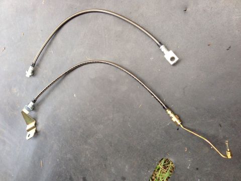 1979 Ford Bronco - Pair of braided stainless steel brake hoses with metal fittings on a dark surface.