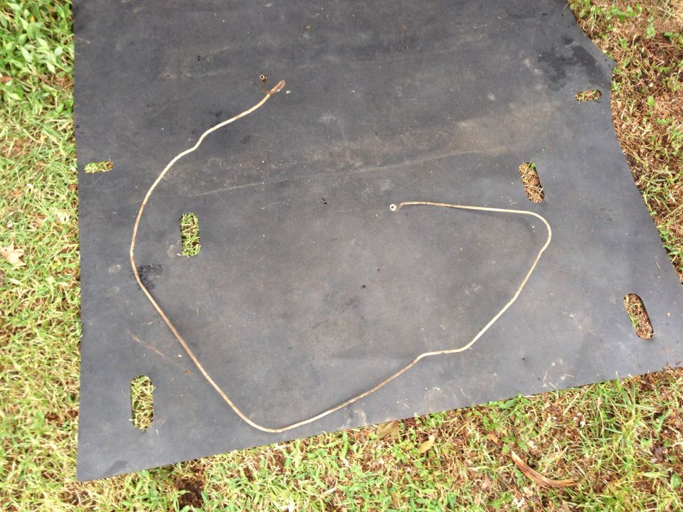 Metal brake line on black mat with grass background. Supermotors.net logo visible