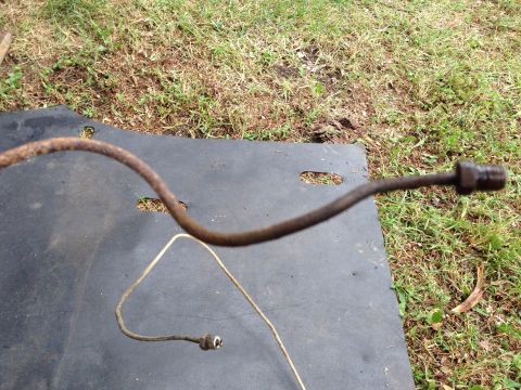 1979 Ford Bronco - A rusty metal brake line lies on a black mat outdoors.