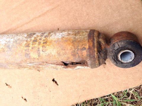 1979 Ford Bronco - A heavily rusted shock absorber, possibly from a vehicle, shows some identifying text and signs of damage.