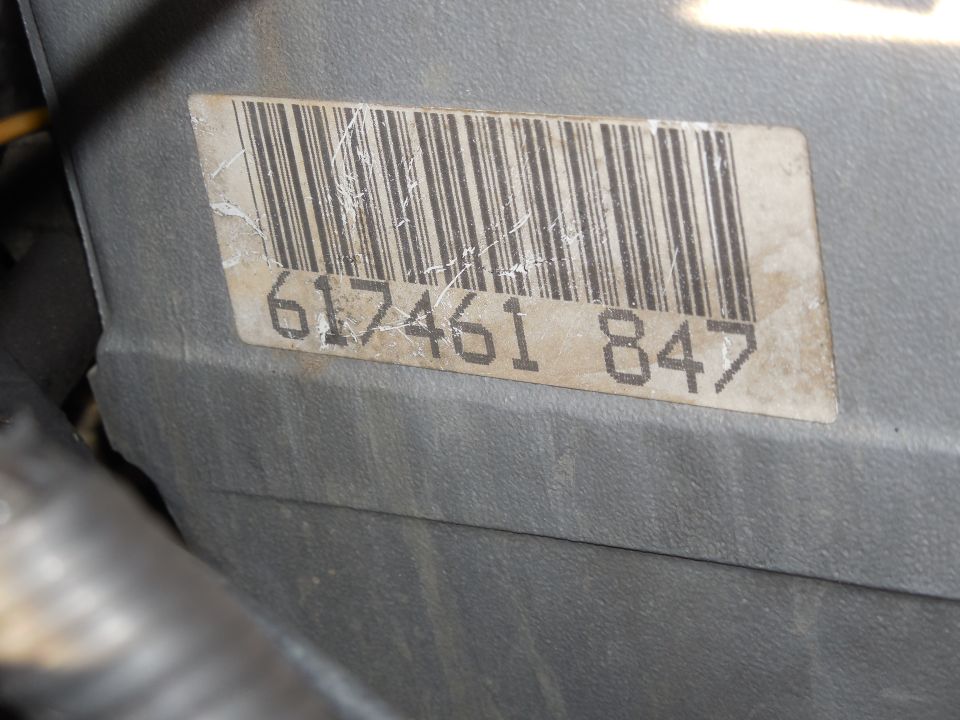 Weathered barcode label 617461 847 on gray plastic engine component housing