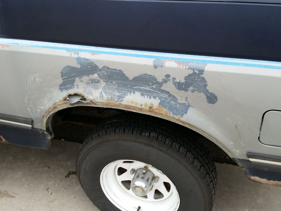 1988 Ford Bronco rear wheel well showing significant rust damage and peeling paint