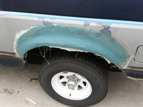 1988 Ford Bronco - Work in progress on a vehicle's fender, showing the application of body filler and fiberglass.