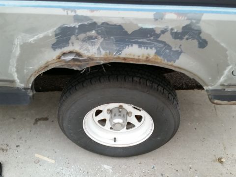 1988 Ford Bronco - The rear wheel well shows significant rust and damage, indicating a need for repair.