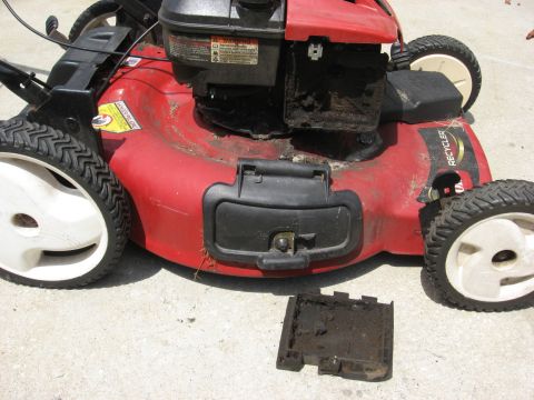 2006 Honda RANCHER - A red lawn mower sits on a concrete surface, showing its engine and detached cover.