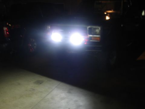 1982 Ford Bronco - A dark 1980s Ford Bronco is seen from the front with its headlights illuminated.