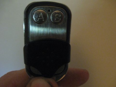 1982 Ford Bronco - A remote key fob with two buttons labeled A and B is held in a hand.
