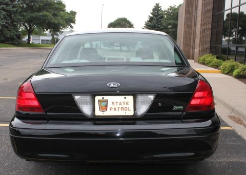 2009 Ford Crown Victoria - Rear view of a black 2009 Ford Crown Victoria, identified by its body style and bearing a State Patrol license plate.