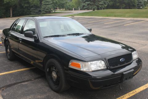 2009 Ford Crown Victoria - A black 2009 Ford Crown Victoria sedan is parked in a lot, showing its front quarter profile.