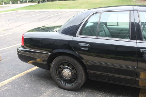 2009 Ford Crown Victoria - This black sedan is parked in a lot, with a view of its rear passenger side and interior.