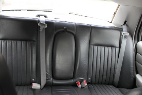 2009 Ford Crown Victoria - The interior rear seat of a vehicle, showing black leather seats and seatbelts.