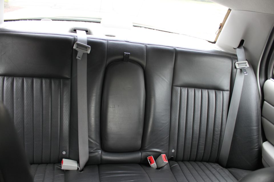 Back seat with black leather upholstery and seatbelts