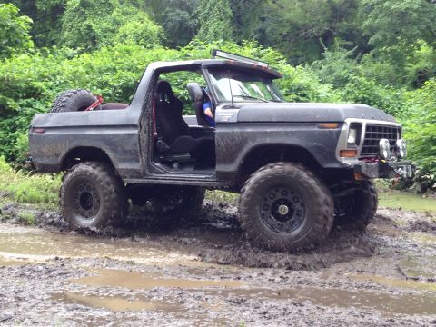 1979 Ford Bronco - This modified Ford Bronco navigates a muddy trail with its doors off and large tires.
